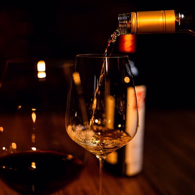 Wine poured into a glass by candlelight, the bottle still tilted