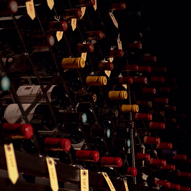 Bottles racked on their sides in the cellar, each shelf tagged with its vintage