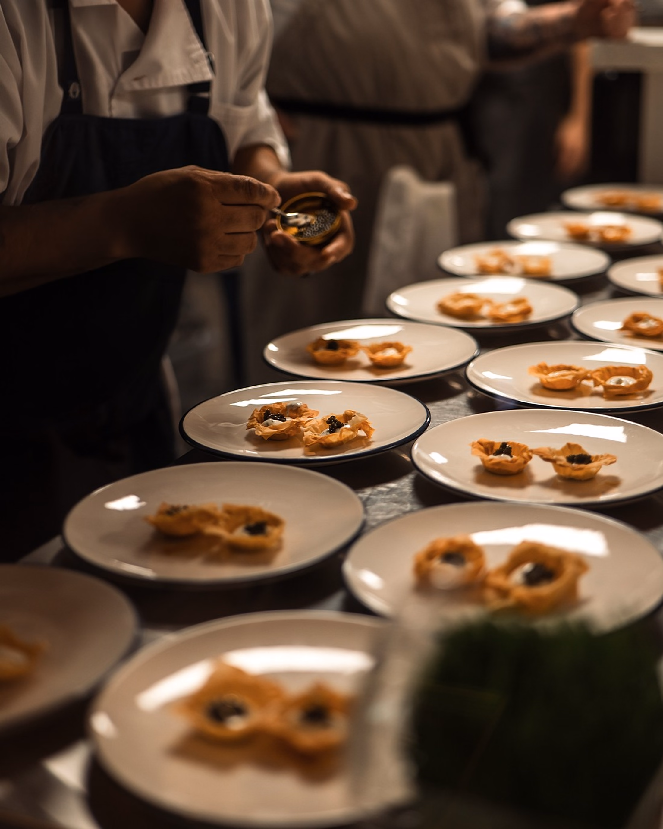 A chef finishing caviar canapés on the pass